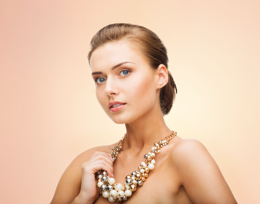 beauty and jewelery concept - beautiful woman wearing statement necklace with pearls