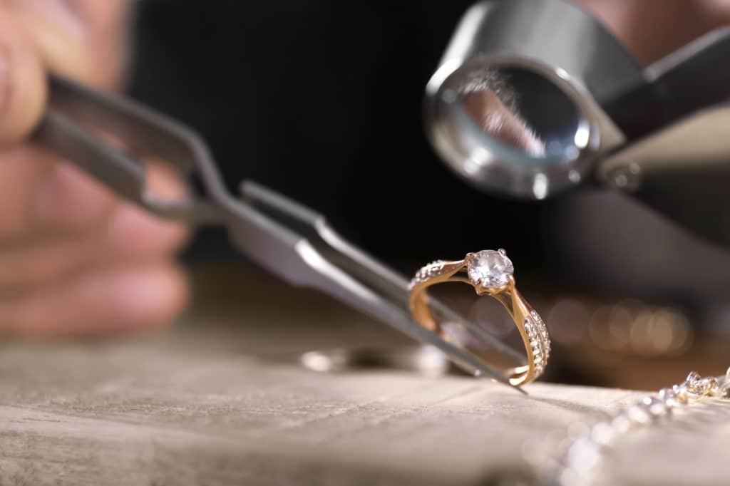 Male jeweler examining diamond ring in workshop, closeup view